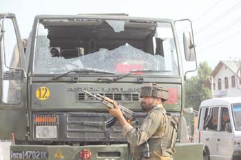 An army men stands guard near a damaged vehicle which was targeted by militants near Hyderpora. Pic: Bilal Bahadur