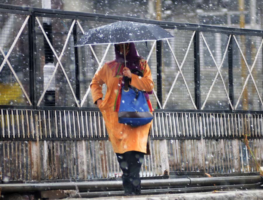 A girl walks in Srinagar as moderate snowfall carpets the city under white.