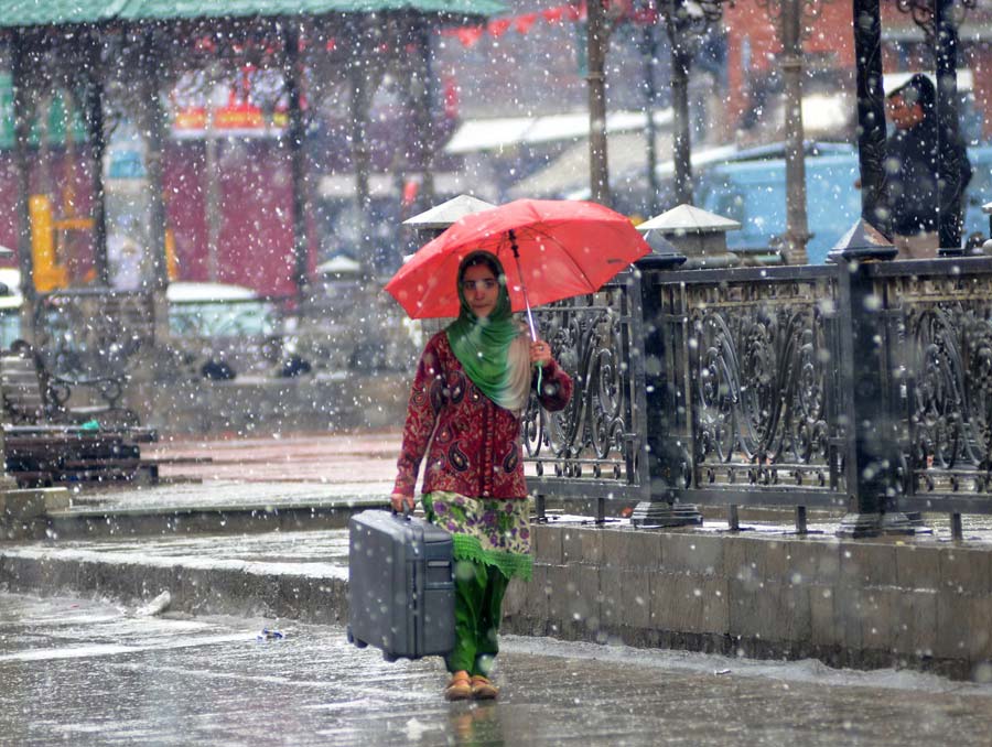 The fresh spell of snowfall has kept traffic mostly off the roads. A girl carrying her luggage through snow covered streets of Srinagar.