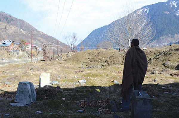 Manzoor Khan standing in Chehal’s graveyard that houses 130 unmarked graves. Pic: Bilal Handoo