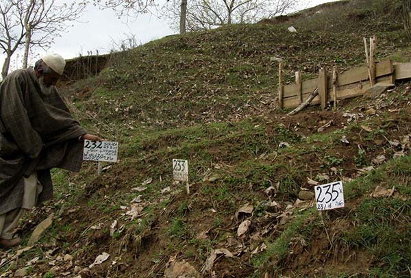An elder pointing towards an unmarked grave