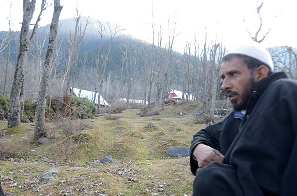 Ghulam Mohammad Bhat sitting in an orchard of unmarked graves in Kichama