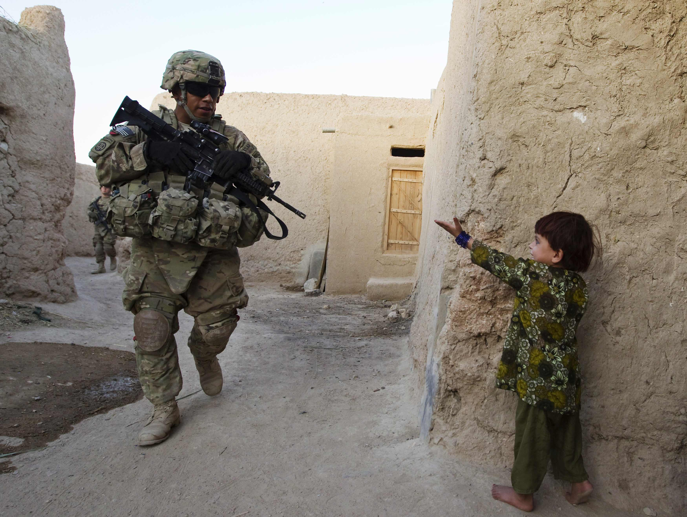 A girl gestures to a U.S. soldier on patrol in the town of Senjaray in the Kandahar province of southern Afghanistan June 1. Some 68,000 U.S. troops remain in Afghanistan as part of Operation Enduring Freedom. (CNS photo/Shamil Zhumatov, Reuters) (Sept. 28, 2012)