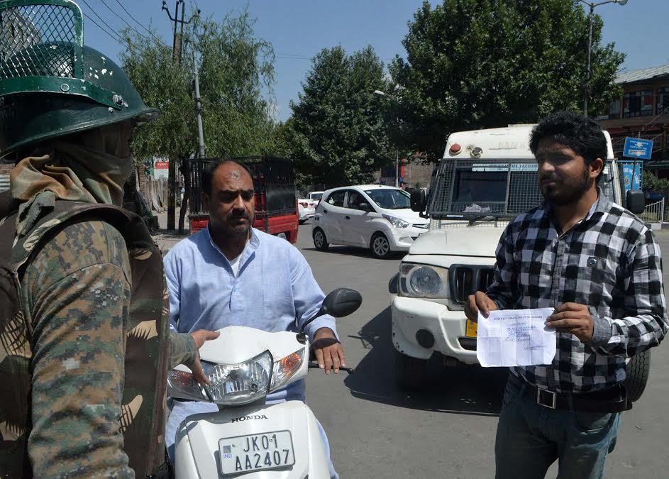 Who is DM? One CRPF man told a Journalist in Old Srinagar. In this picture, a civilian showing his curfew pass to para-military CRPF personnel to let them go. (KL Image: Mehraj Bhat)