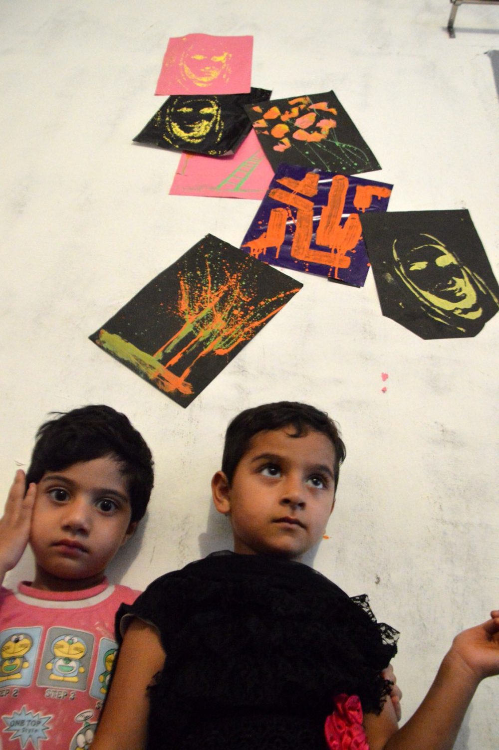 Kids standing in backdrop of their sketches.