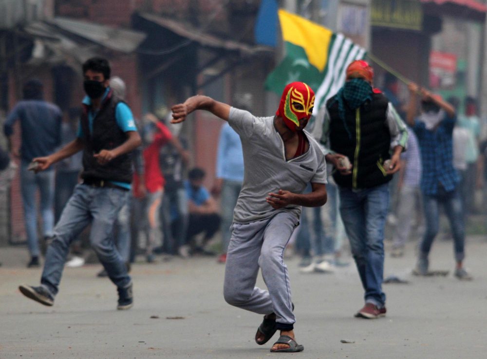 A masked Kashmiri protester throws stone at policemen during a protest in Srinagar. (Photo: Bilal Bahadur/KL)