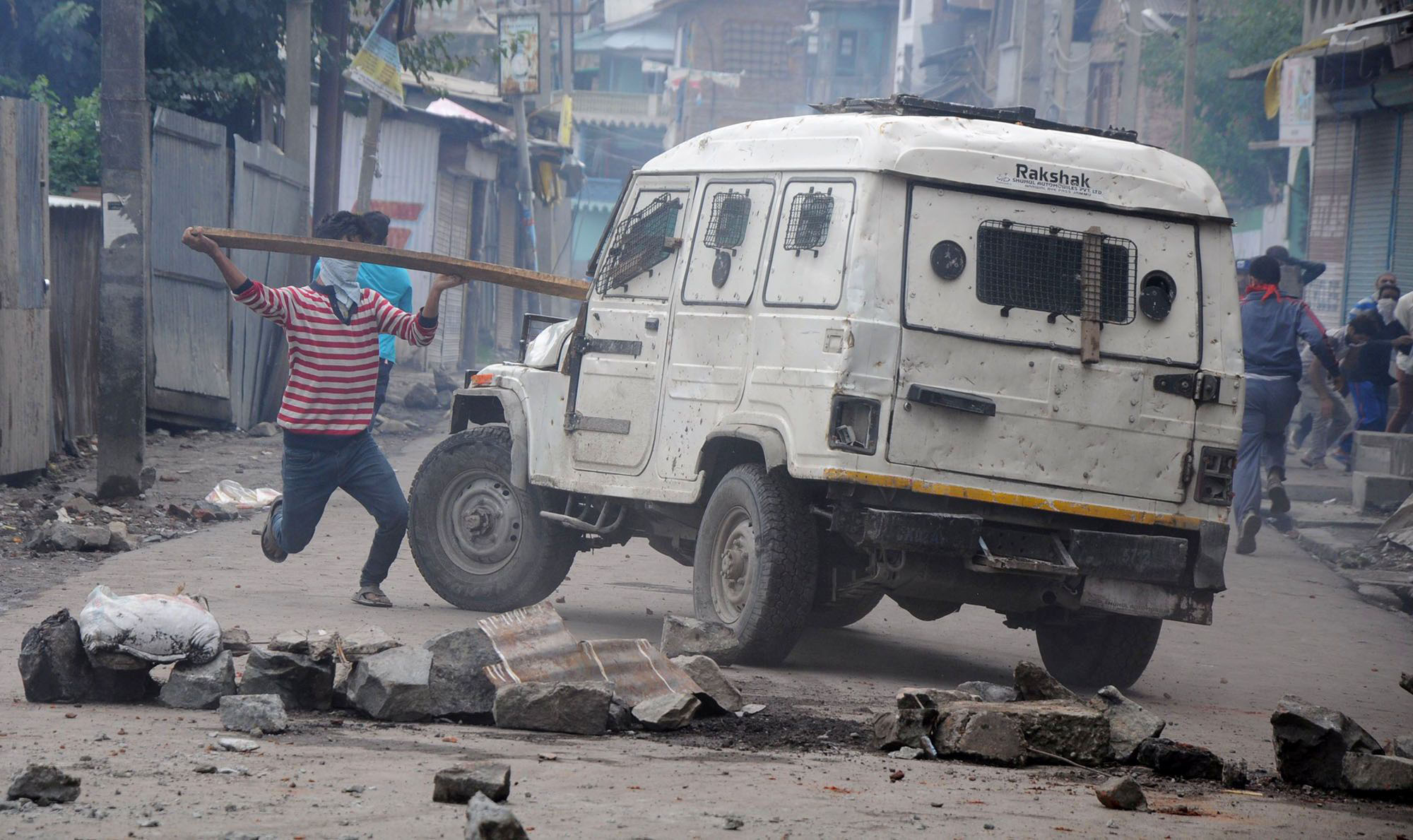A youth attacking a police jeep with wooden plank at Batamaloo. (Photo: Bilal Bahadur/KL)