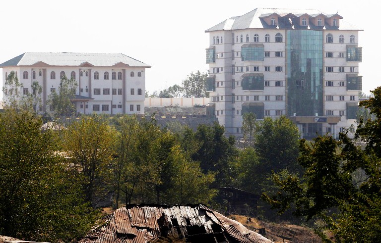 Broken glasses and smoke is seen coming out from the EDI Hostel building (right) where suspected militants are reported to have taken refuge during a gun-battle in Pampore, on the outskirts of Srinagar, Monday, Oct. 10, 2016. (KL Image: Bilal Bahadur)