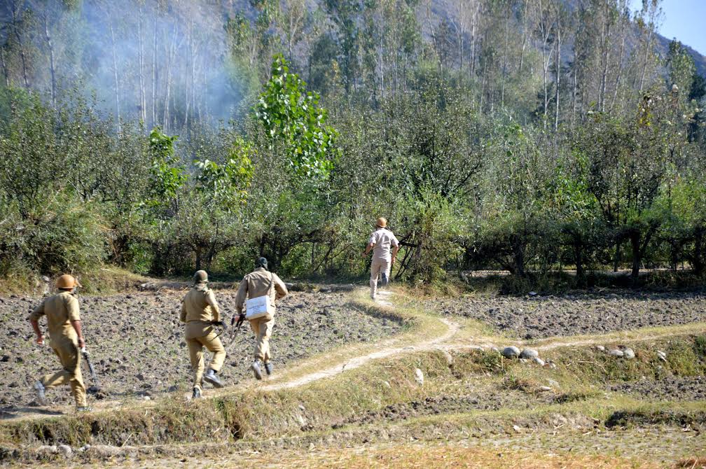 Men inn uniform chase people through rice fields in Livar area of Islamabad district on Oct 10, 2016 after people attempted to hold a freedom rally in the area. (KL Image: Shah Hilal)