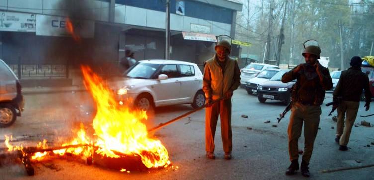 Cops removing buring tyres from the main road in Sonawar where locals were protesting against the arrest of their Imam. Pic: Mehraj Bhat