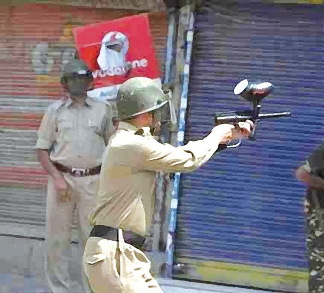 A policeman firing controversial pellet gun towards civilian protesters in Srinagar.