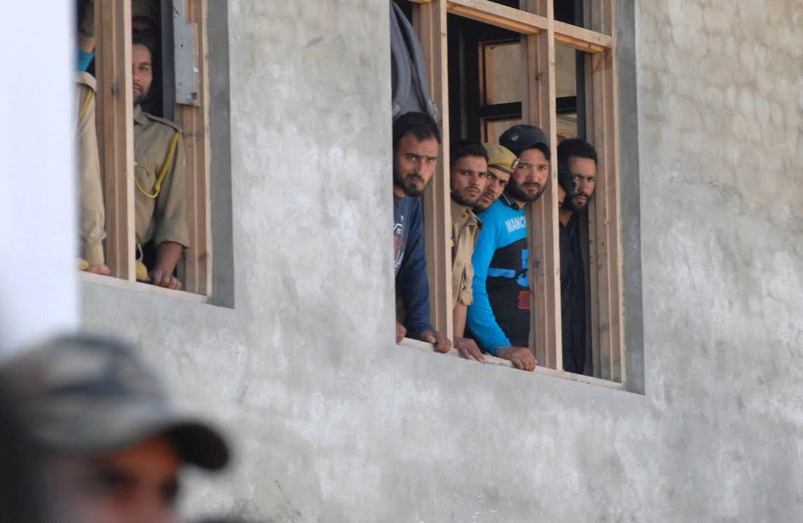 Policemen watch from windows inside a police headquarters during a wreath laying ceremony in Srinagar on June 16, 2017, after two policemen were killed and another was injured in attacks by militants. Two policemen were killed and another injured in two different attacks by militants on June 15. PHOTO BY BILAL BAHADUR