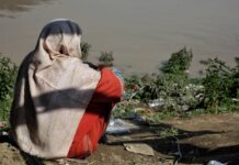 A woman in the Batwara area of Srinagar district watches rescuers on the River Jhelum shore following the capsizing of a boat carrying 19 people, resulting in six fatalities, three missing, and the remainder rescued.(KL image: Numan Bhat)