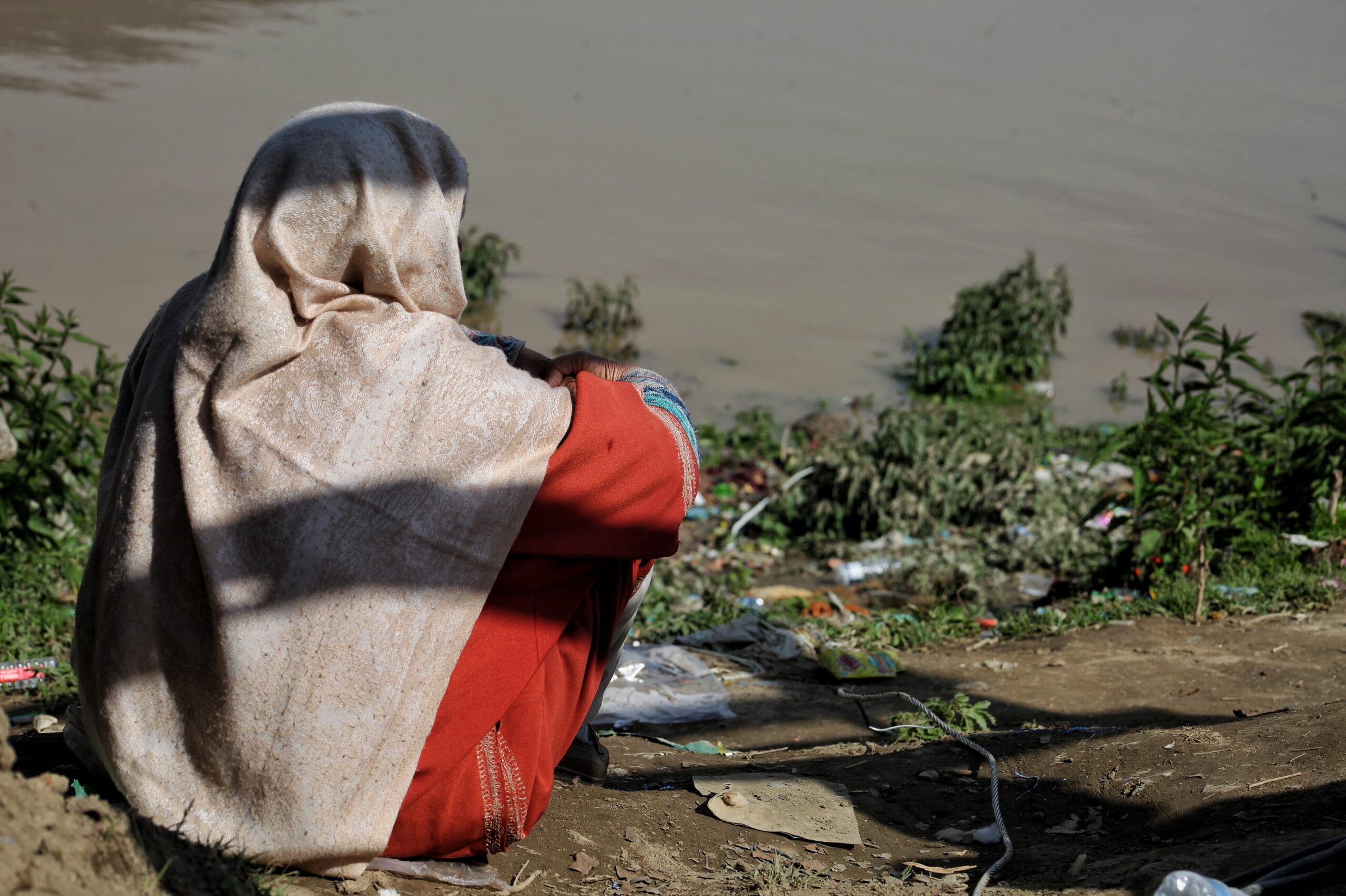 A woman in the Batwara area of Srinagar district watches rescuers on the River Jhelum shore following the capsizing of a boat carrying 19 people, resulting in six fatalities, three missing, and the remainder rescued.(KL image: Numan Bhat)