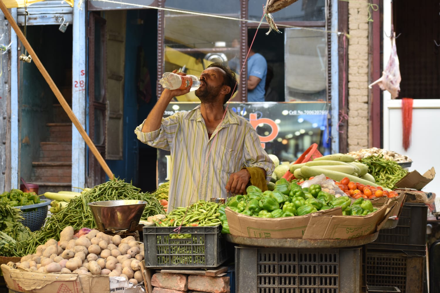 A vendor drinks water to beat the heatwave at a market in Bandipora, North Kashmir, on July 28, 2024. (KL Image: Muqeet Mubashir)