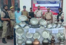 Police personnel display the 53 recovered copper utensils along with the two accused arrested in connection with a theft case in Chandoosa, Baramulla