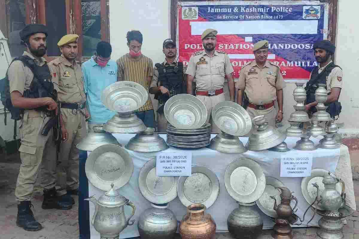 Police personnel display the 53 recovered copper utensils along with the two accused arrested in connection with a theft case in Chandoosa, Baramulla